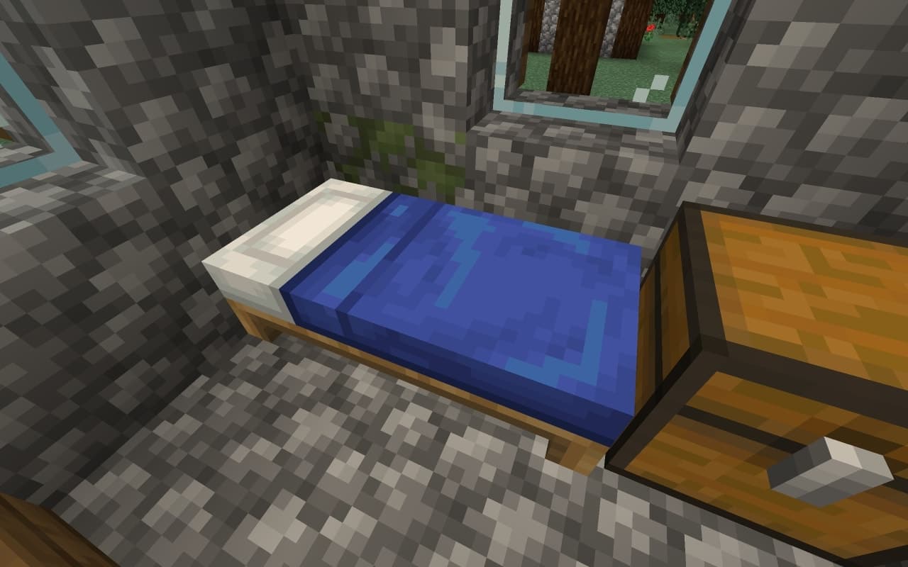 Ein blaues Bett neben einer hölzernen Lagertruhe in einem Minecraft-Dorfhaus aus Bruchstein.