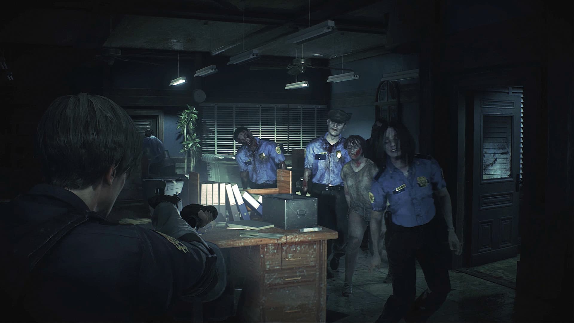 Leon zielt in Resident Evil 2 zwischen Schreibtischen und Stühlen mit einer Pistole auf näher kommende Zombies.