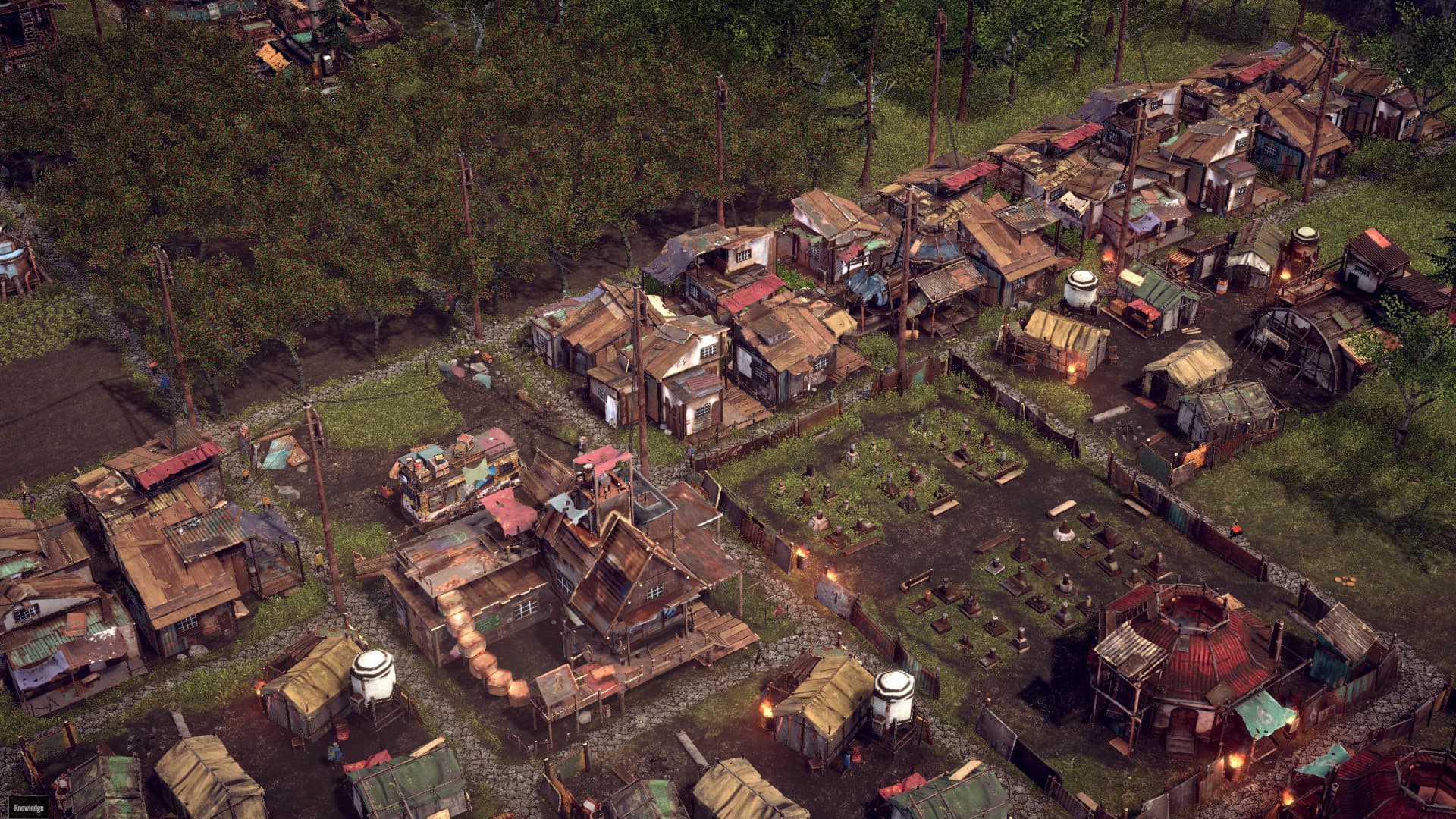 Endzone - A World Apart settlement with rows of patched-metal homes, paths, residents and a fenced burial ground.