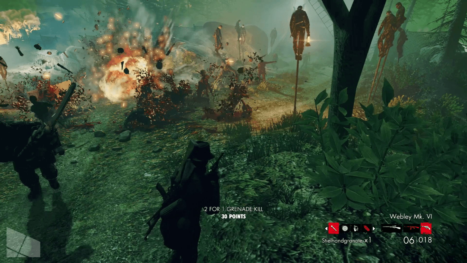 Überlebende stehen in einem Waldgebiet von Zombie Army Trilogy Zombies gegenüber, die von einer Explosion erfasst werden.