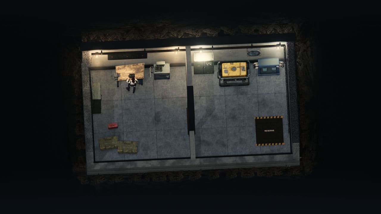 Der Alpha-Schutzraum von Zombie Defence von oben: ein Bewohner an der Werkbank, Versorgungsmaschinen und ein markierter Reservebereich, umgeben von Fels.